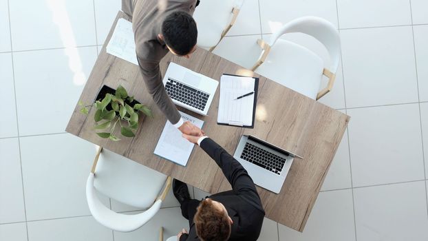 two businessmen sitting on a chair and watching something on a laptop