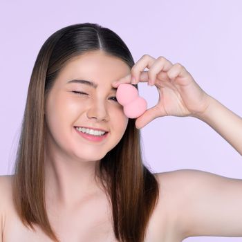 Facial cosmetic makeup concept. Portrait of young charming girl applying dry powder foundation. Beautiful girl smiling with perfect skin putting cosmetic makeup on her face.