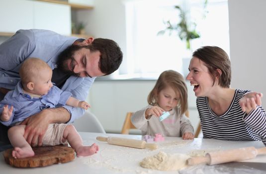 Happy parents playing with their children in the kitchen