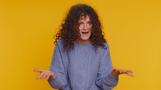 Dissatisfied curly haired woman asking reason of failure, expressing disbelief irritation, feeling bored, disappointed in result, bad news. Young teen girl isolated alone on yellow studio background
