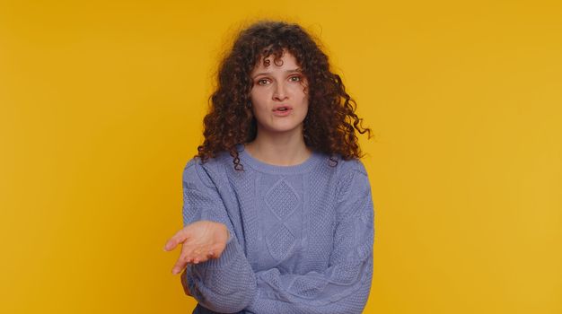 Quarrel. Displeased curly haired woman gesturing hands with irritation and displeasure, blaming scolding for failure, asking why this happened. Young teen girl isolated on yellow studio background