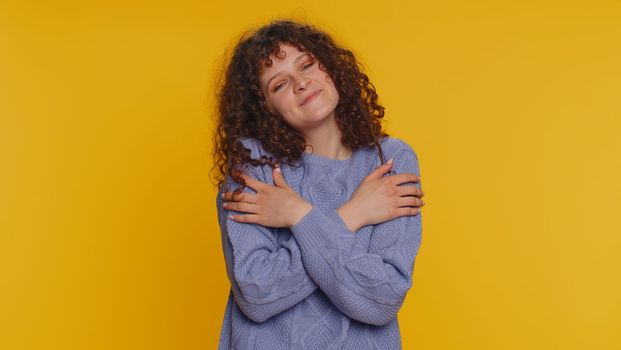 Come to me, I want to embrace you. Happy smiling curly haired woman spread hands and give hug to you. Pleasant expression, love feelings. Young teen girl isolated alone on yellow studio background