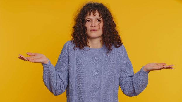 I dont know what to say. Confused woman feeling embarrassed about ambiguous question, having doubts, no idea, being clueless and uncertain. Young curly haired girl isolated on yellow studio background