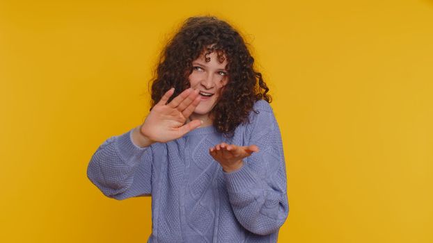 Cheerful rich millennial woman showing wasting or throwing money around hand gesture, more tips dreaming about big profit body language. Young curly haired girl isolated on yellow studio background