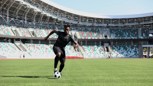 African American man playing football on the stadium field.