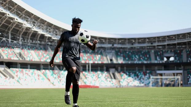 African American man playing football on the stadium field.