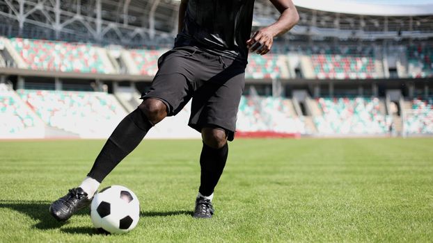 African American man playing football on the stadium field.