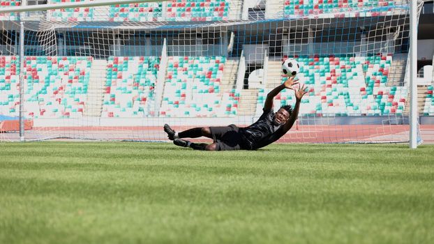 Football goalkeeper catches the ball in the stadium. game concept