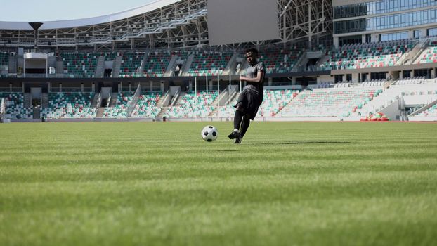 African American man playing football on the stadium field.