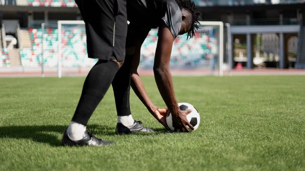 African American man playing football on the stadium field.