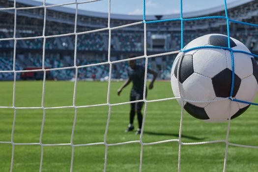 African American soccer player kicking ball inside large stadium