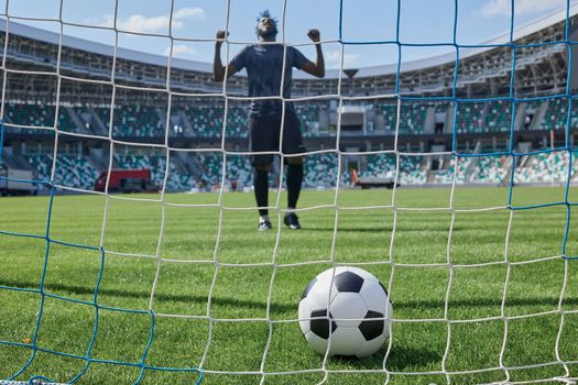 African American soccer player kicking ball inside large stadium