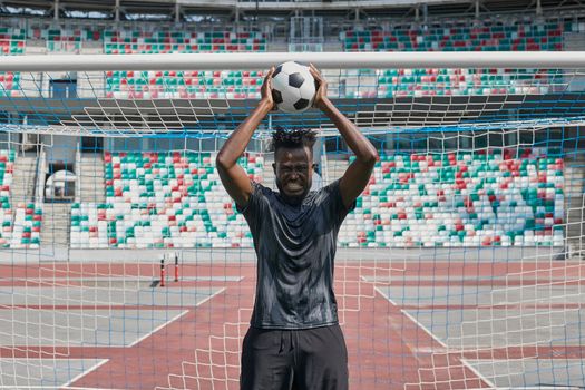 african american football player holding the ball in his hands at the stadium