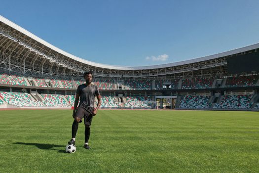 Man holding soccer ball with his foot in the stadium