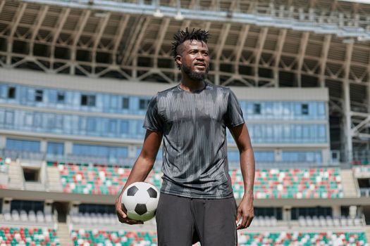 confident black football player holding the ball in his hand
