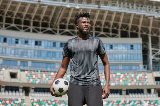 confident black football player holding the ball in his hand