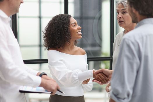 Smiling multiethnic businesspeople shaking hand in office.