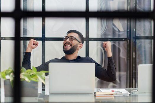 Business man sitting at his desk in the office with a laptop