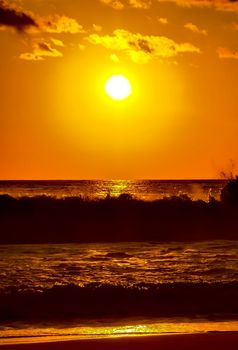 Beautiful stunning colorful and golden sunset in yellow orange red on beach and big wave panorama in tropical nature in Zicatela Puerto Escondido Oaxaca Mexico.