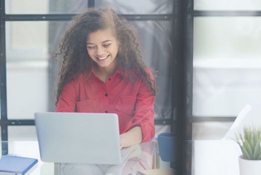 Portrait of Young Successful Caucasian Businesswoman Sitting at Desk Working on Laptop Computer in City Office