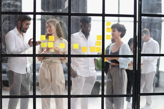 colleagues discuss and stick notes on the glass in the office