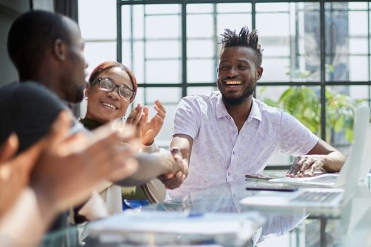 team of young african people in the office shaking hands