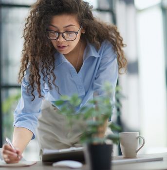 A young woman makes a report in the office. Woman writing notes for educational project in business