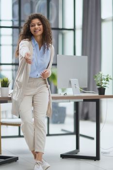 Woman shaking hands while sitting on a desk in the office