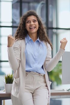 Excited young girl celebrating success business achievement result, looking camera