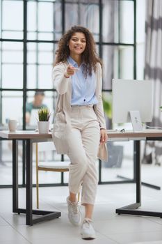 Portrait of a young confident woman pointing at you in the office