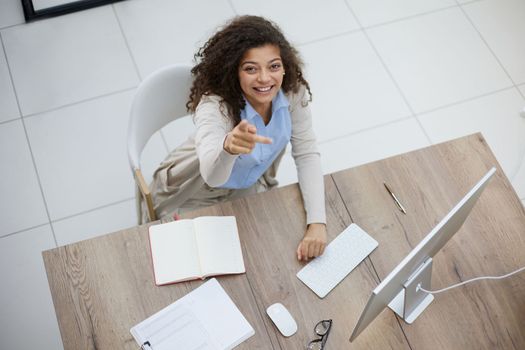 Image of young beautiful joyful woman smiling while working with laptop in office