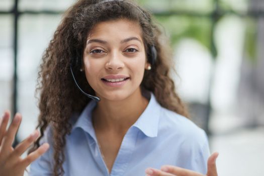 Beautiful smiling woman consultant in headphones with a microphone. Remote work from home.