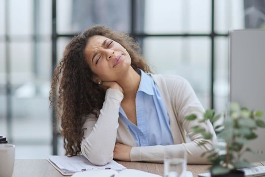 Businesswoman with headache sitting at the table in the office