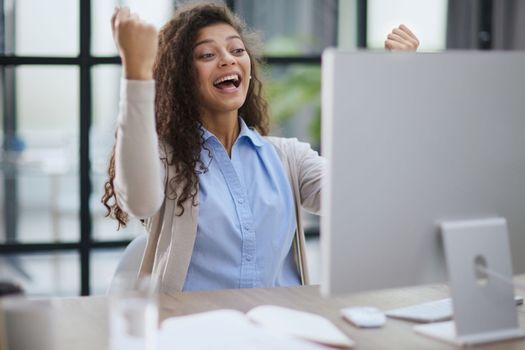 expressive young woman open mouth checking discounts for online shopping sitting at desktop .