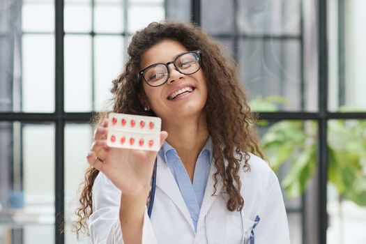 Portrait of young female doctor in white coat at workplace