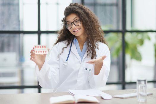 Portrait of young female doctor in white coat at workplace