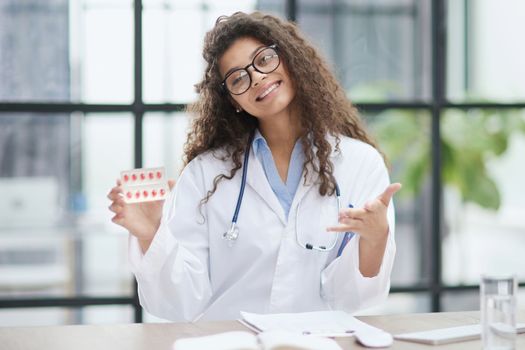 Portrait of young female doctor in white coat at workplace