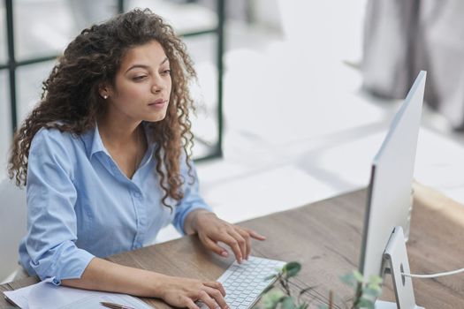 Smiling businesswoman or helpline operator with headset and computer at office