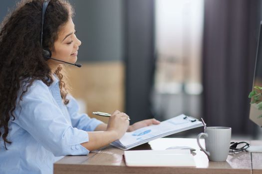 Side view of cheerful operator in headset in office