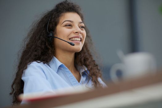 Brunette business woman using headset to communicate and advise people in customer service office. Call centre.