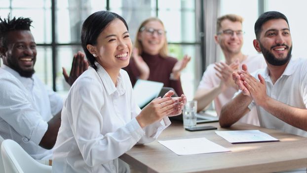 a group of diverse business people sitting together at a table cheering celebrating success