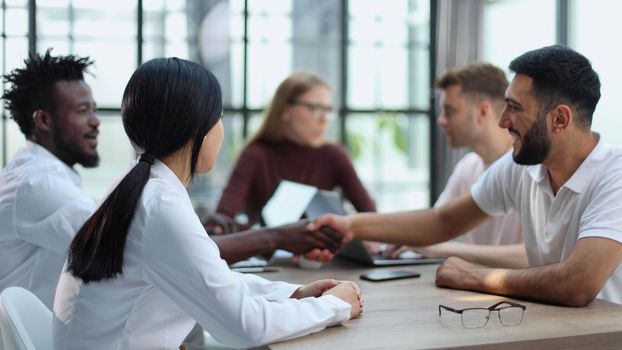 Welcome to our team. Shaking hands while working in the creative office