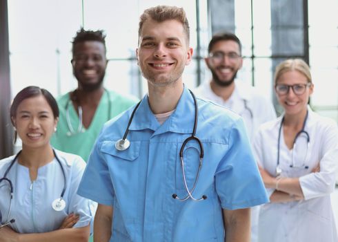 Smiling group of scientists in modern office with male leader, mixed race