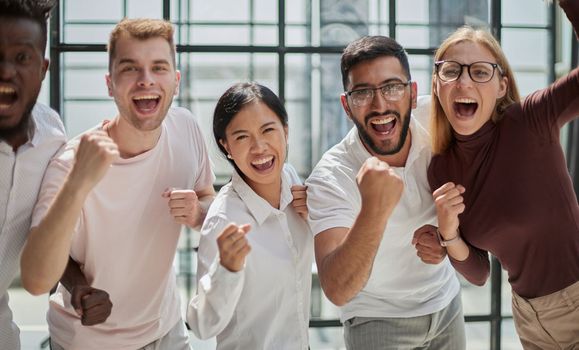 Group of mono-ethnic corporate employees clenching their fists celebrating success