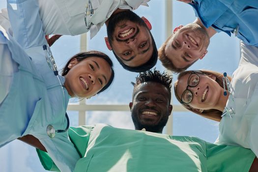 Successful team of medical doctors are looking at camera and smiling while standing in hospital