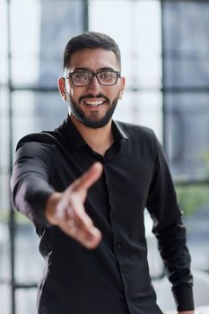 smiling businessman reaching out for a handshake