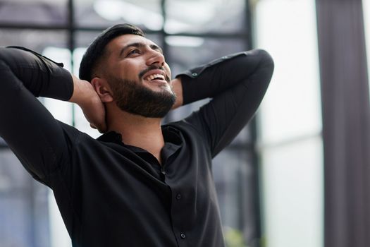 Portrait of relaxed businessman in modern office.Business young man relax after work of office window with business district view.