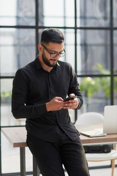 Young casual Businessman holding and using smartphone for sms messages