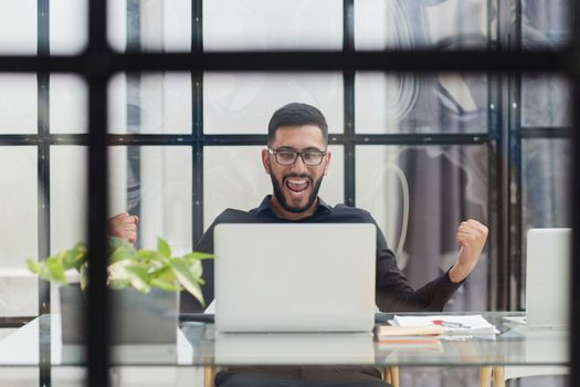 Business man sitting at his desk in the office with a laptop