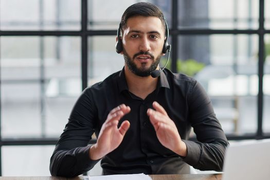 Young handsome male customer support phone operator with headset working in his office.